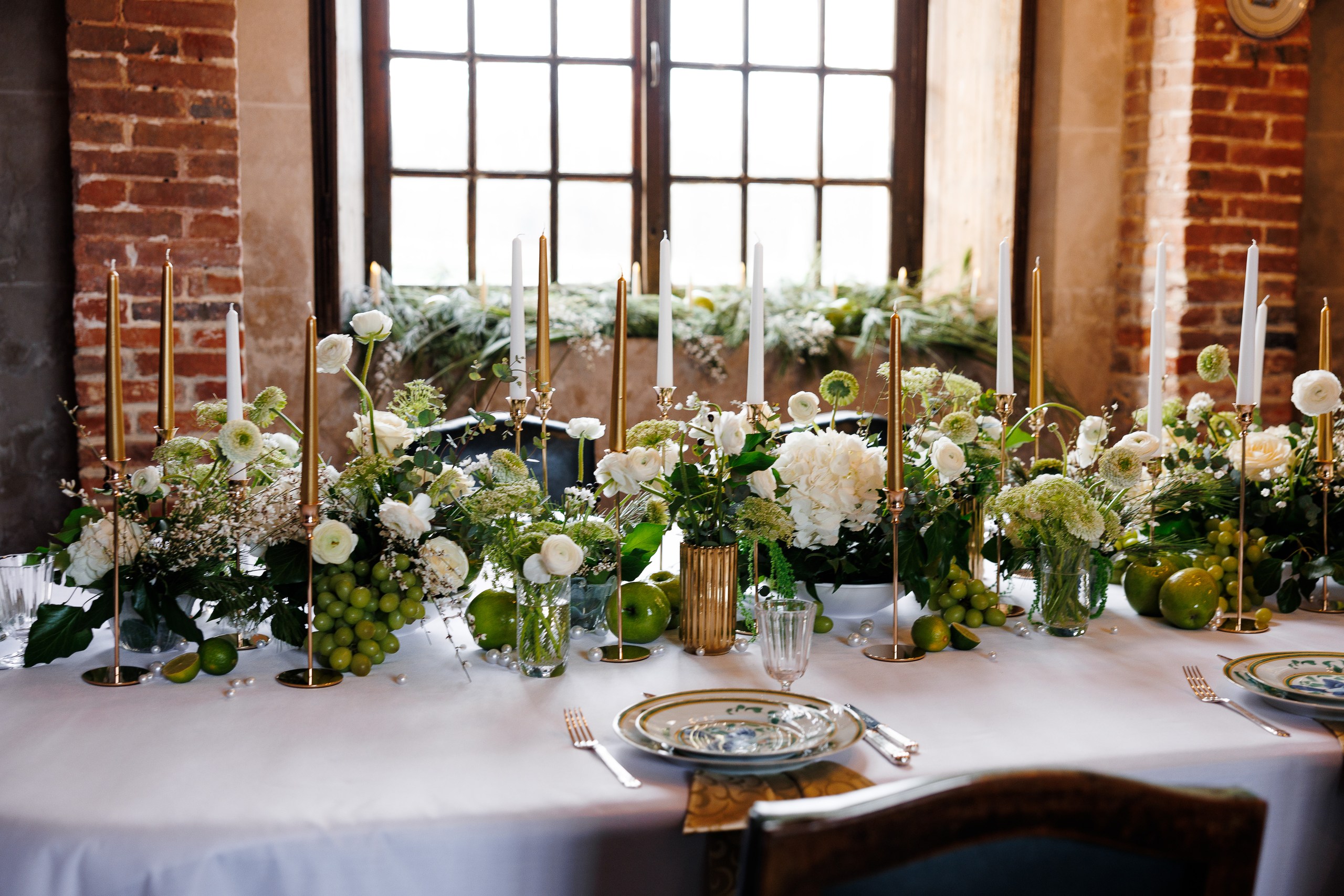 A reception table styled with gold candlesticks, greenery and white flowers at Château de Bonnemare